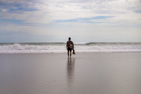 Handsome tanned tattooed sexy man with a naked torso in a flying poreo on the ocean at sunset.