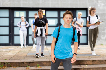 Positive teenager walking in the street carrying a bag on one shoulder