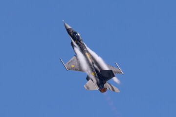 Close view of a F-16 Fighting Falcon in a high G maneuver, with condensation streaks at the wing roots and around the nose, with afterburner on