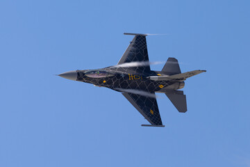 Close view of a F-16 Fighting Falcon in a tight turn, with condensation streaks at the wing roots