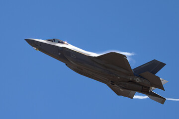 Fototapeta na wymiar Very close tail view of a F-35A Lightning II with afterburner on and condensation streaks