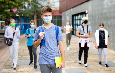 Portrait of teenager in protective mask with backpack going to school lessons on sunny autumn day. New lifestyle during coronavirus pandemic