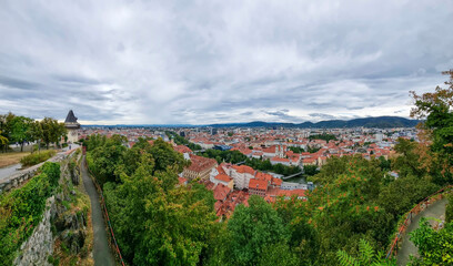 Fototapeta na wymiar Cityscape of old town of Graz and the Clock Tower (Grazer Uhrturm), famous tourist attraction in Graz, Steiermark, Austria, in cloudy summer day.