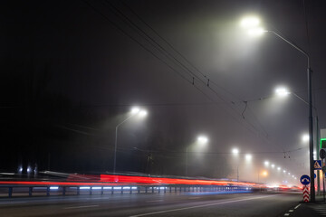 View empty dark night blue foggy misty rainy highway city road backlight red traces low poor visibility cold spring autumn season. Seasonal bad rainy weather accident danger warning car fog light