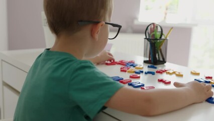 back view baby kid boy in glasses completing word mama with alphabet letters on white desk. learning at home, early education, abc colorful letters, first words. concept family education children - Powered by Adobe