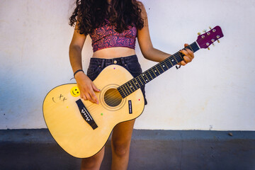 girl playing acoustic guitar in a white wall