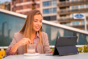 Blonde executive, businesswoman or financier woman having a decaffeinated coffee breakfast with her tablet