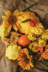 Rustic autumn still life. Colorful autumn flowers, pumpkins, pattypan squashes on burlap on wooden table. Seasons greeting card, space for text. Happy Thanksgiving! Harvest time in countryside