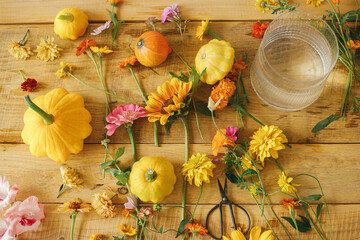 Stylish autumn flat lay. Colorful autumn flowers, pumpkins, pattypan squashes, scissors on rustic wooden table. Seasons greetings. Harvest time in countryside. Happy Thanksgiving! Hello Fall