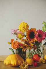 Happy Thanksgiving! Colorful autumn flowers, pumpkins, pattypan squashes composition on wooden table against rustic background. Seasons greeting card. Harvest in countryside. Hello Fall