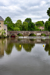 Fototapeta na wymiar View of the Sillé bridge and the Creusot grain water mill over the river Sarthe on a cloudy spring day, Fresnay-sur-Sarthe, France