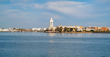 View of the tourist town and lighthouse of Isla Cristina from Isla del Moral with the  Carreras River near the mouth of the sea, Huelva, Andalusia, Spain