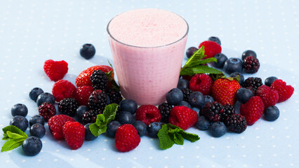 Healthy vitamin milkshake with mix of ripe berries and mint leaves served in glass