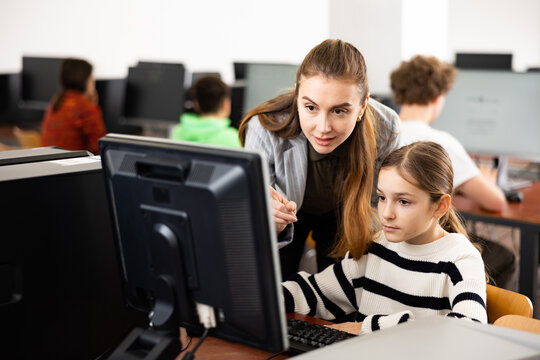 Positive woman teacher together with the girl teaches how to work on the computer