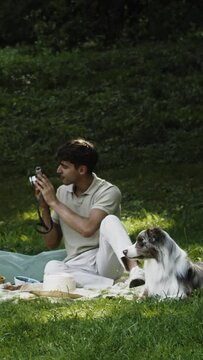 a man with a dog taking photos at a picnic in the park