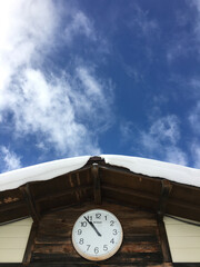 スキー場　雪の屋根と時計と青空