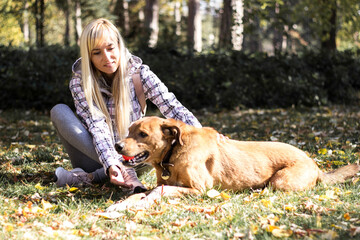 Happy young adult woman enjoys time at a park with her dog