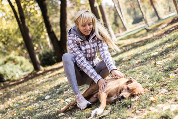 Happy young adult woman enjoys time at a park with her dog