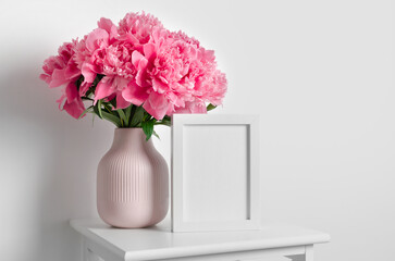 Blank frame mockup with peony flowers in white interior