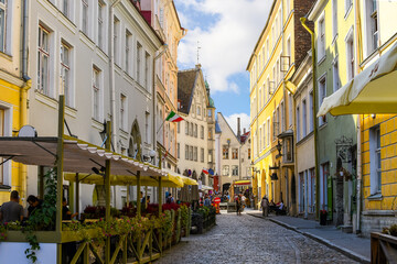 Fototapeta na wymiar A picturesque cobbled street of sidewalk cafes and shops near the Bishop's House in the medieval old town of Tallinn, in the Baltic region of Northern Europe.