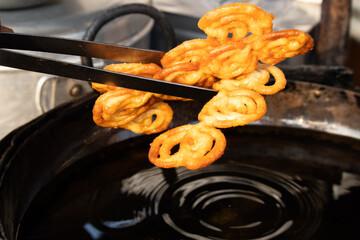 Holding Deep Fried Indian Jalebi Also Known As Jilapi, Jilebi, Jilipi, Zulbia, Jerry, Zalebi, Mushabak Mithai Made Of Fermented Maida And Besan. Dhaba Halwai Taking Fried Cooked Golden Reddish Sweet © Rangeecha
