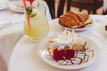 Deliciosa tarta de limón y merengue acompañada por limonada con menta. Al fondo medialuna con...