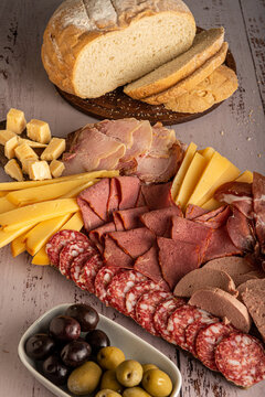 Picada, plato t&iacute;pico de embutidos, quesos y aceitunas, aperitivo argentino y espa&ntilde;ol, sobre una tabla de madera.