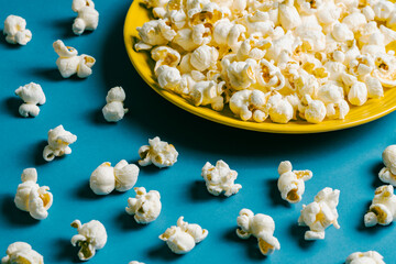 Popcorn on a yellow plate on blue background, Food or snack, Health or salt