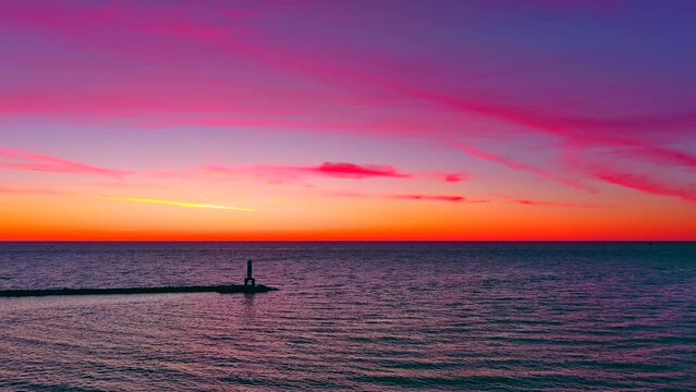 Incredible sunrise sky over lighthouse, drones flying and filming. Silhouetted people fishing.
