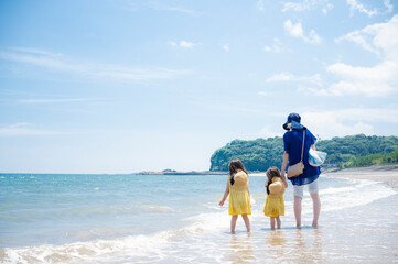 真夏の海の砂浜と青い空と親子