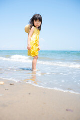 Fototapeta na wymiar 夏の海の砂浜で遊ぶ5歳の女の子