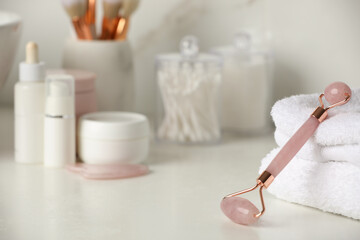 Fototapeta na wymiar Natural face roller, gua sha tool and cosmetic products on counter in bathroom