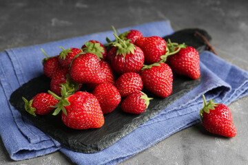 Many delicious ripe strawberries on grey table