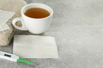 Mustard plasters, thermometer, towel and tea on light grey table, space for text