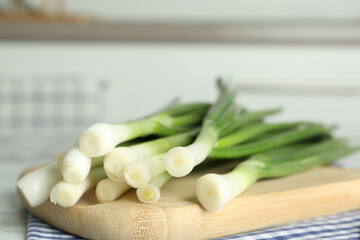 Fresh green spring onions on wooden board, closeup