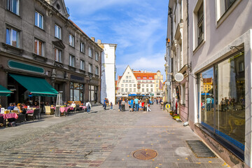 A picturesque cobbled street of sidewalk cafes and shops leading to Town Hall Square in the medieval old town of Tallinn, in the Baltic region of Northern Europe.