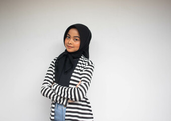Fototapeta premium Portrait of smiling young Asian Muslim woman in black and white stripe cardigan looking confident isolated on a white