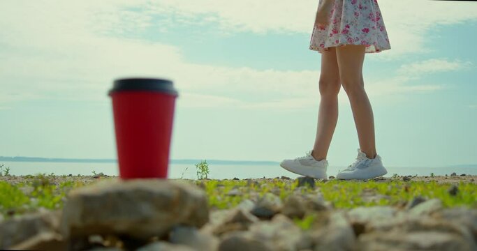 Against The Background Of A Paper Cup, Beautiful Legs Are Dancing A Shuffle Dance, Daylight Hours, A Short Skirt, Out Of Focus On The Near Object.