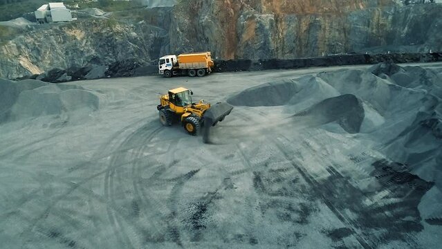 Aerial view of wheel loader working on construction site. Wheel bulldozer loading soil in scoop.
