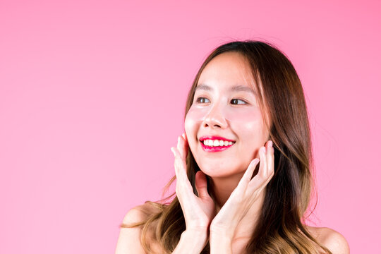 Facial skin care makeup of Beauty attractive young asian woman applying eye tretment rejuvenation on her under eyes on the pink backgound