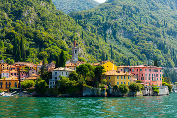 Picturesque view of small city of Varenna on shore of Lake Como on background of mountain on summer day, Italy