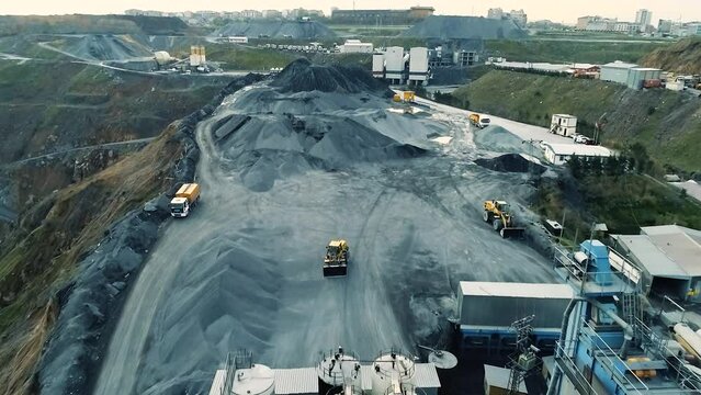 Aerial view of wheel loader working on construction site. Wheel bulldozer loading soil in scoop.