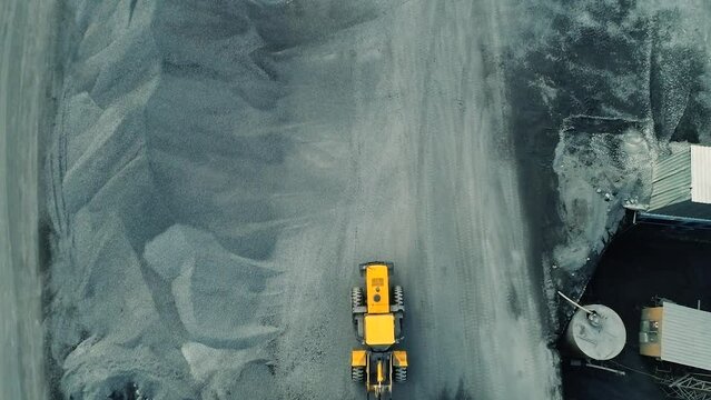 Aerial view of wheel loader working on construction site. Wheel bulldozer loading soil in scoop.