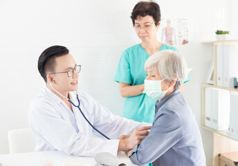 Fototapeta premium Asian doctor talk with old female patient about disease symptom, he use stethoscope listening on chest of patient, elderly health check up