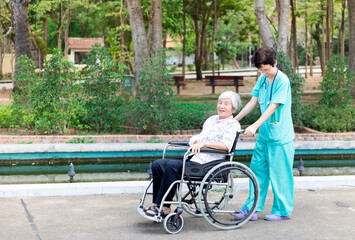 Asian health worker drive a wheelchair of old patient, happy hospital, rehabilitation activity