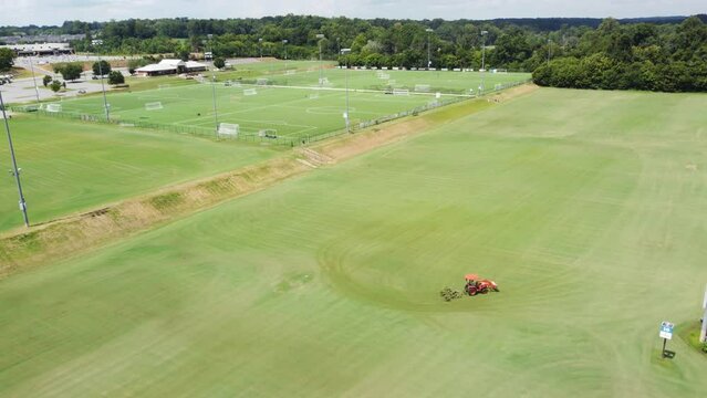 Orange Tractor mowing Sports complex fields