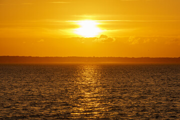 Deep orange sunset over Isle of Wight Bay, with light reflecting on the water.