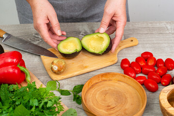 cook preparing avocado for serving. various vegetables and spices on the kitchen table.Close up.