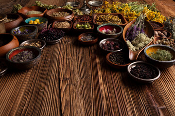 Natural medicine background. Assorted dry herbs in bowls, mortar and plants on rustic wooden table.