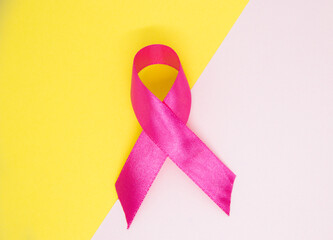 pink ribbon isolated on white and yellow background, breast cancer awareness symbol